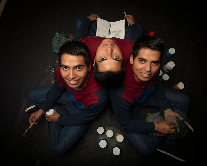 Leonel, Lorenzo y Luis recostados en círculo, con pinturas y pinceles